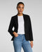 Person wearing a black blazer, white shirt, and blue jeans on a plain background