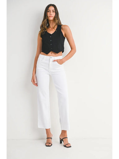 Woman wearing a black sleeveless top and white pants on a white background