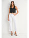 Woman wearing a black sleeveless top and white pants on a white background