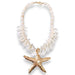 Necklace with white shell beads and a gold starfish pendant on a white background