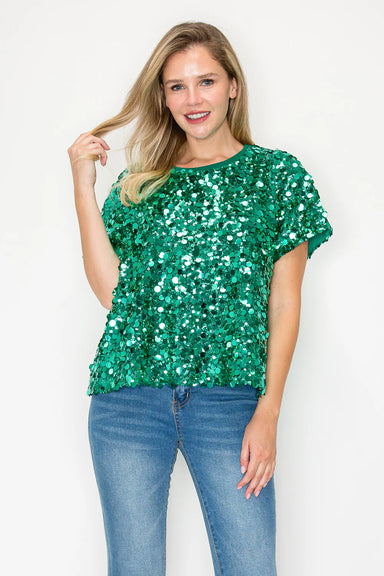 Woman wearing a green sequin top and blue jeans on a white background
