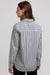 A woman shown from the back wearing a long-sleeve button-up shirt with vertical black and white stripes, paired with black pants, against a light gray studio background.