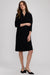 A woman modeling a black three-quarter sleeve midi dress with a split neckline, paired with black slingback heels, against a light gray studio background.