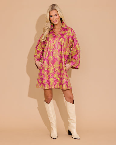 Woman wearing a pink and gold patterned dress with white knee-high boots on a beige background