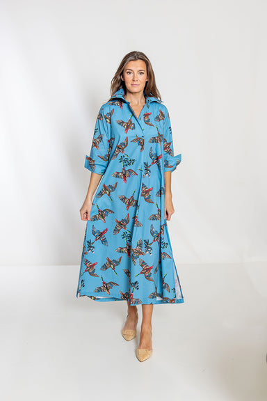 Woman wearing a blue dress with bird pattern on a white background