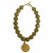 Green beaded bracelet with a gold coin charm on a white background