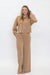 A woman modeling a matching two-piece lounge set in a warm tan color, featuring a long-sleeve quarter-zip top and wide-leg pants, against a plain white studio background.