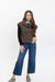 A woman modeling a sleeveless brown button-front vest over a black long-sleeve top, paired with blue jeans and brown slip-on shoes, against a plain white studio background.