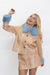 A woman modeling a beige faux deer-print jacket and matching skirt set with light blue faux fur trim on the collar and cuffs, set against a plain white studio background.
