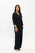 A woman modeling a black two-piece outfit consisting of a button-front long-sleeve top and matching wide-leg pants, photographed against a seamless white studio background.
