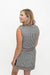 A woman wearing a sleeveless black and white gingham mini dress with red piping trim, shown from a three-quarters back view against a white studio background.
