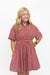 A young blonde girl modeling a short-sleeve red and white vertically striped button-down dress with a smocked waist and side pockets, posed against a solid white background.