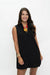 A woman modeling a sleeveless black V-neck mini dress with a small front slit, paired with a red and yellow statement necklace and gold bracelets, against a plain white studio background.