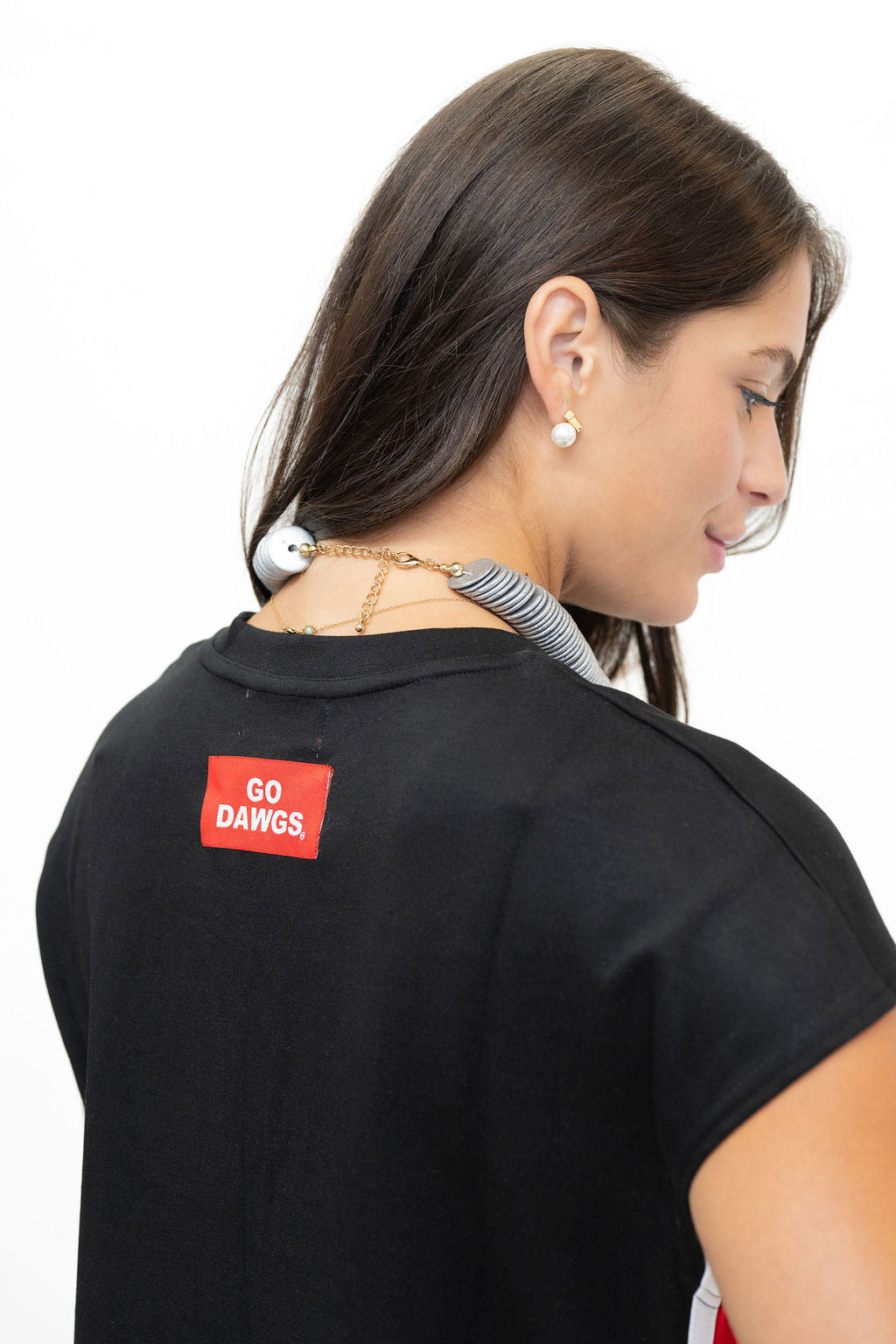 A woman shown from the back wearing a black t-shirt with a red rectangular patch that reads 'GO DAWGS' in white text.