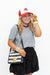 A woman posing in a gray t-shirt, black skirt, red and white trucker hat, and a black and white striped crossbody bag with a gold lion patch.