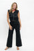 A woman modeling a black sleeveless vest and matching wide-leg pants set with white contrast stitching, photographed against a plain white studio background.