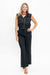 A woman modeling a black sleeveless vest and matching wide-leg pants set with white contrast stitching, photographed against a plain white studio background.