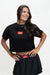 A woman modeling a black short-sleeve crop top and matching black skirt set, both featuring a red rectangular chest logo that reads 'GO DANGERS'. The photo is taken against a clean, light off-white studio background.