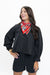 A woman wearing a black cropped bomber jacket, black denim shorts, and a red bandana with a black tiger print around her neck, posing against a solid white background.