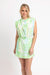Woman wearing a light green sleeveless dress with a floral pattern on a white background