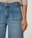 Close-up of blue jeans with a hand touching the pocket on a neutral background