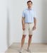 Man wearing a light blue polo shirt and beige shorts against a plain background