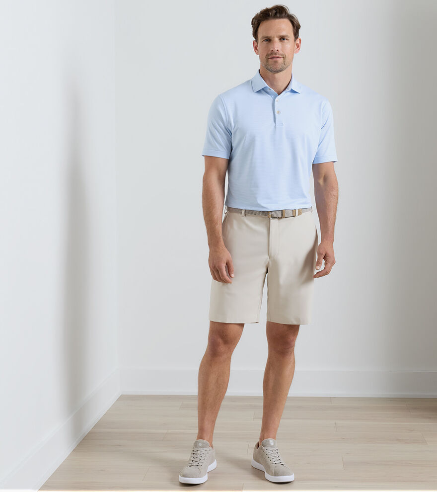 Man wearing a light blue polo shirt and beige shorts against a plain background