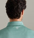 Rear view of a man wearing a mint green patterned collared shirt against a neutral gray background.