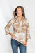 Woman wearing a patterned blouse with a plain background