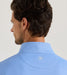 Man wearing a blue shirt with a visible brand logo on a light gray background