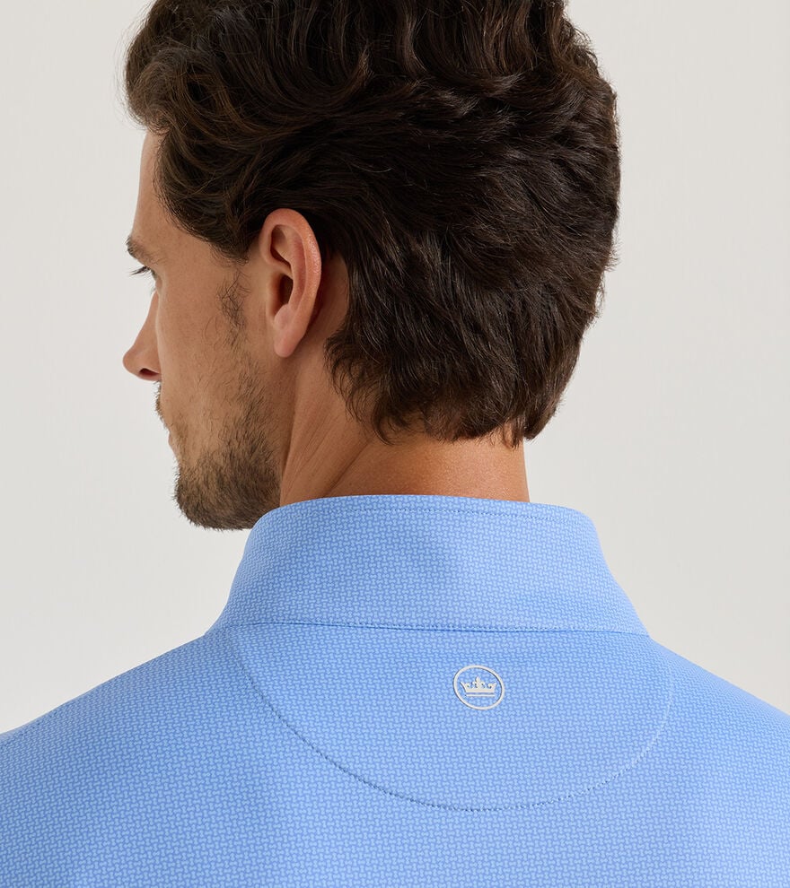 Man wearing a blue shirt with a visible brand logo on a light gray background