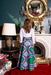 Woman in a colorful skirt standing in a room with a large ornate mirror and fireplace.