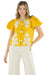 Woman wearing a yellow top with white floral patterns on a white background