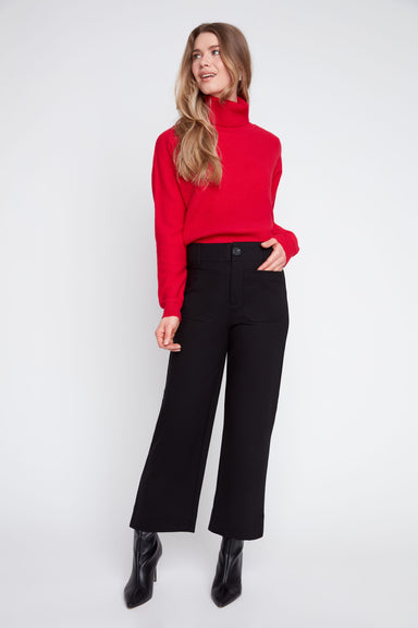 Woman wearing a red sweater and black pants on a white background