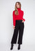 Woman wearing a red sweater and black pants on a white background