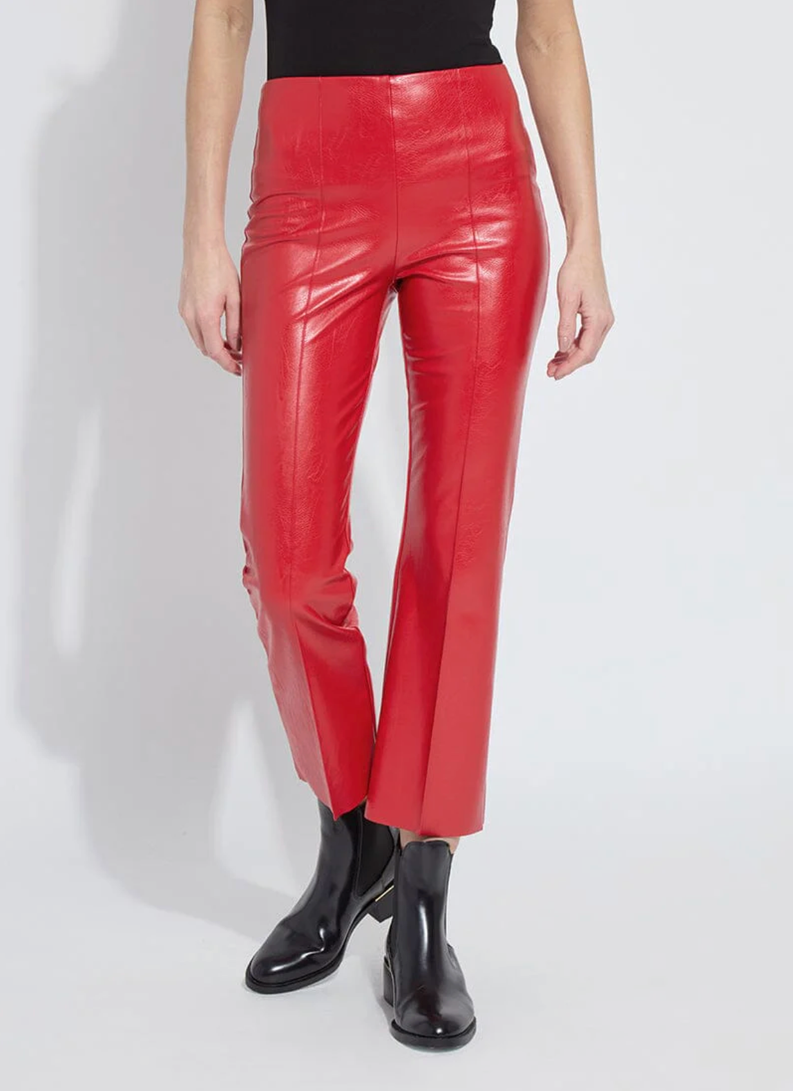 Person wearing red vinyl pants and black shoes on a white background