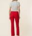 A model shown from the back wearing bright red cropped jeans and a light gray t-shirt, standing against a solid cream background.
