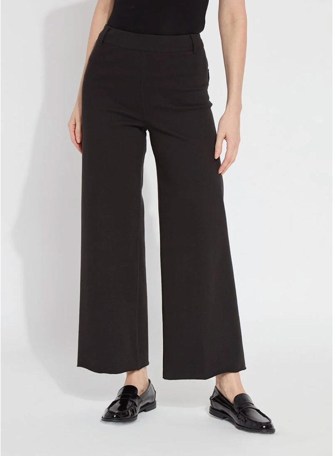 Person wearing black wide-leg pants on a white background