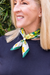WOMAN WEARING SCARF AROUND NECK WITH ROUND OBJECT HOLDING IT IN PLACE 