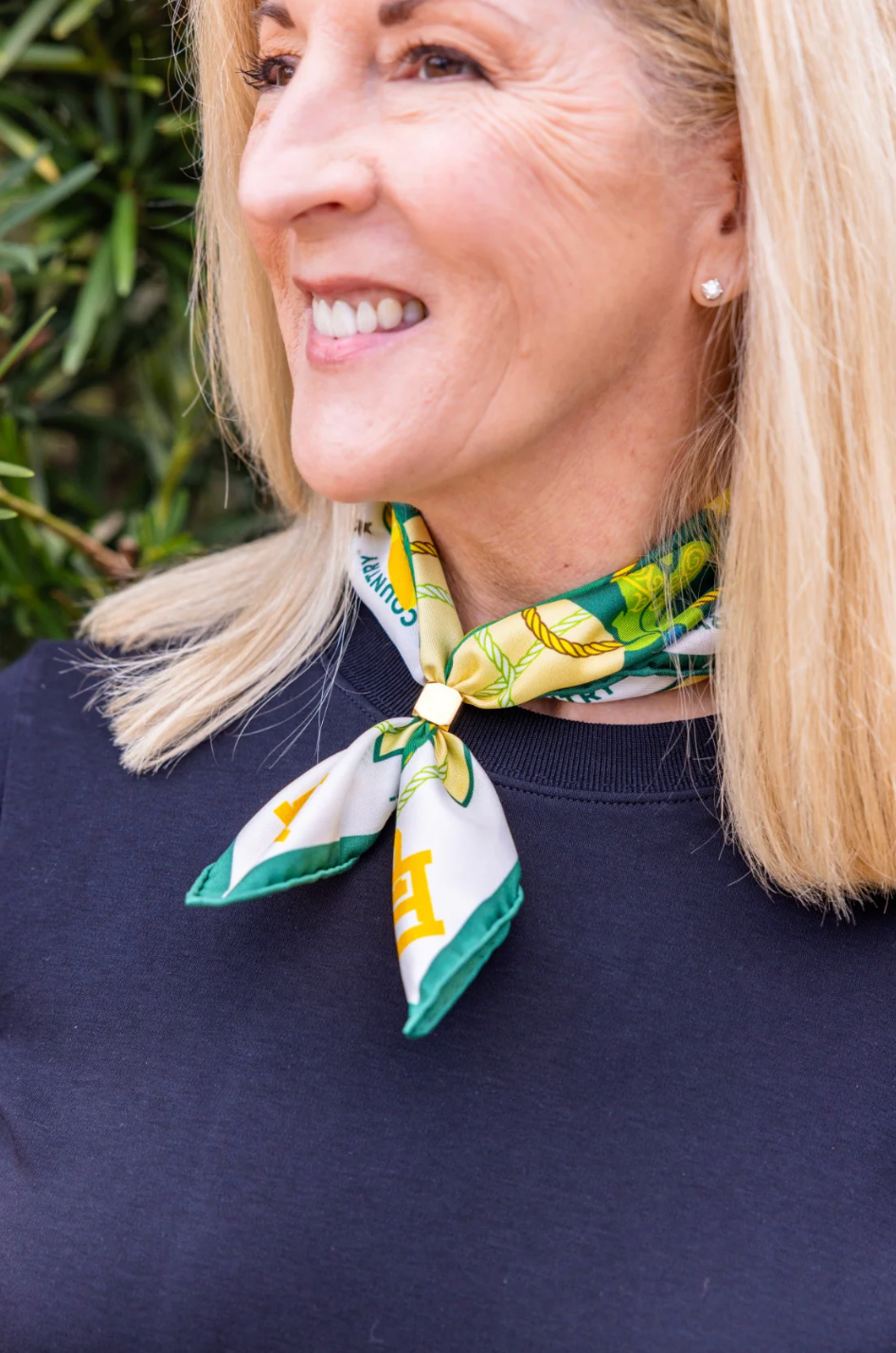 WOMAN WEARING SCARF AROUND NECK WITH ROUND OBJECT HOLDING IT IN PLACE 