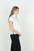 SIDE VIEW OF MODEL WEARING SOLID WHITE V NECK SHORT SLEEVE BLOUSE WITH POPPED COLLAR AND DETAIL ON V NECK