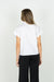 REAR VIEW OF MODEL WEARING SOLID WHITE V NECK SHORT SLEEVE BLOUSE WITH POPPED COLLAR AND DETAIL ON V NECK