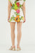 Person wearing a skirt with tropical fruit and flower print on a white background