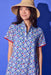Woman wearing a patterned dress and straw hat against a blue background