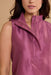 Close-up of a woman wearing a sleeveless satin-like top in a dusty mauve-pink color with a high stand collar and a partial front zipper.