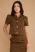 Woman wearing a brown jacket with gold buttons on a beige background