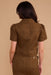 Person wearing a brown jumpsuit against a beige background