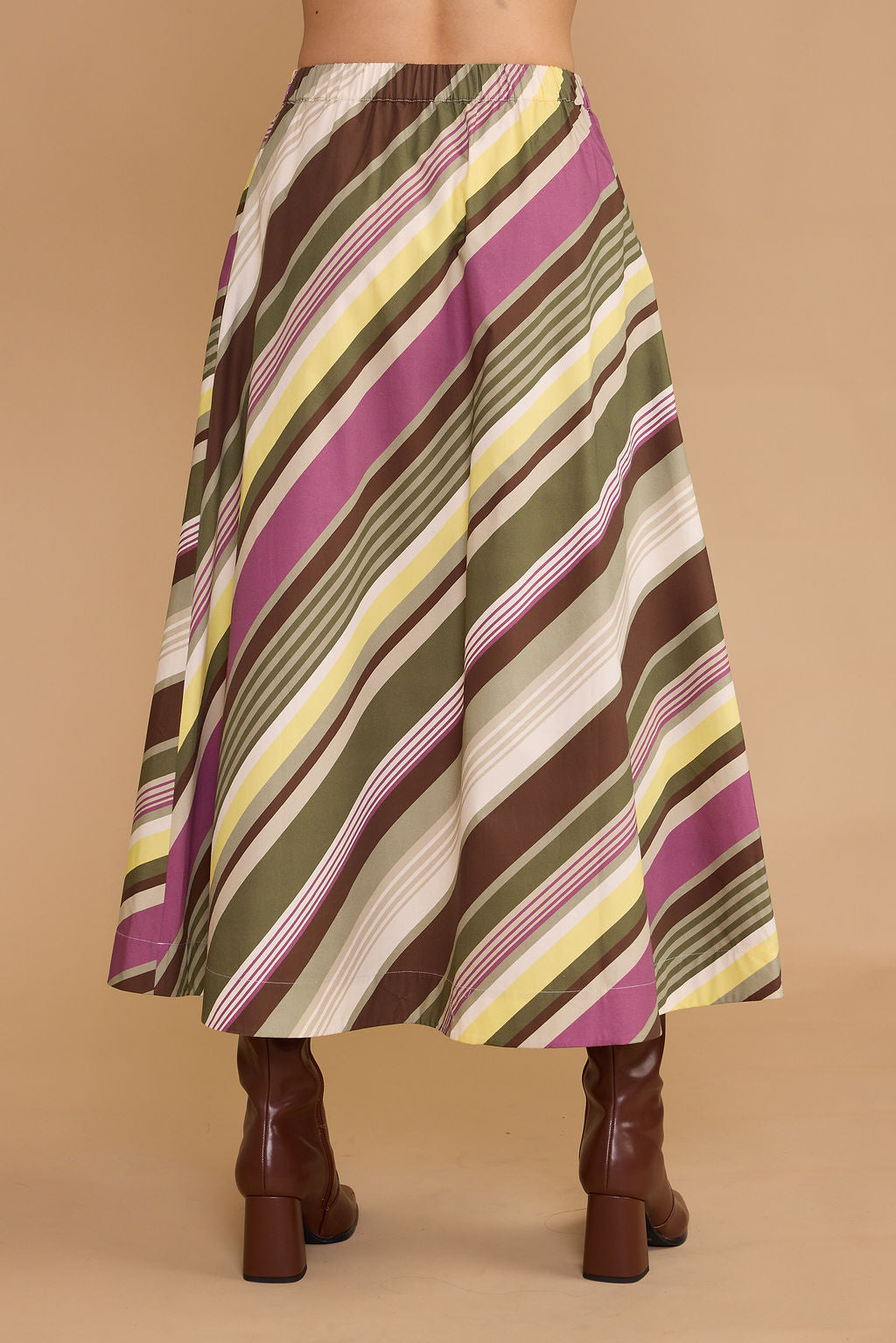 A midi skirt with diagonal stripes in olive green, magenta, brown, yellow, and cream, shown on a model from the back against a solid beige background.