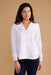 Woman wearing a white blouse against a beige background