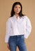 Woman wearing a white shirt and blue jeans against a beige background